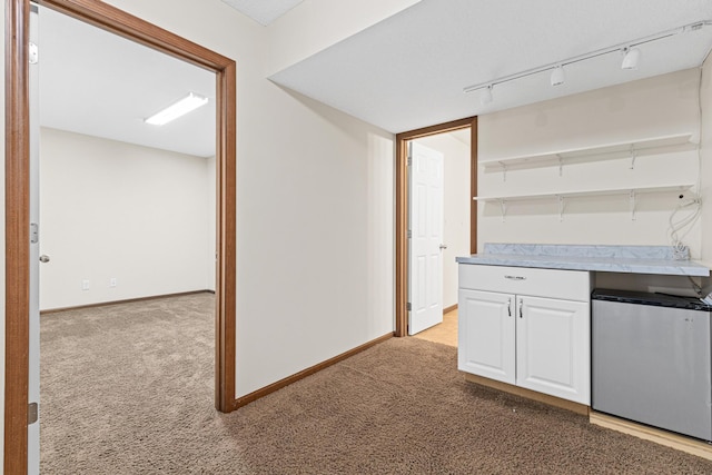 kitchen with white cabinets, stainless steel fridge, and light carpet