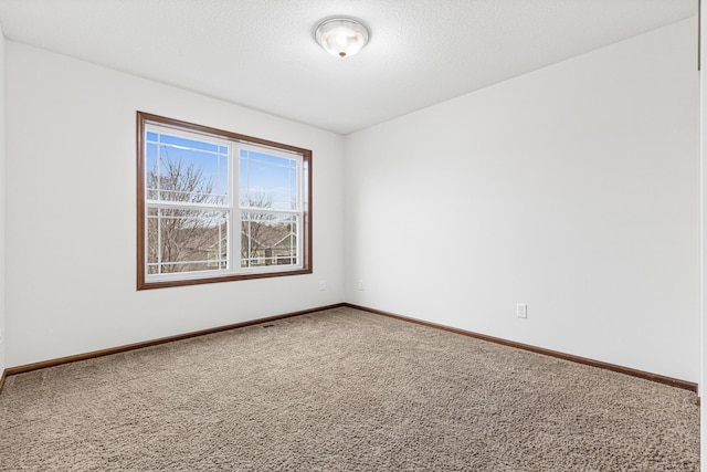 carpeted empty room featuring a textured ceiling