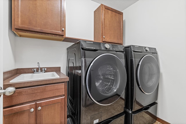 laundry area with washing machine and dryer, sink, cabinets, and a textured ceiling