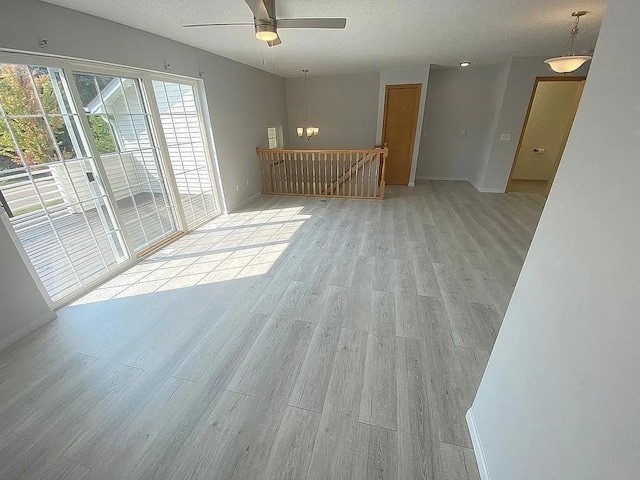 unfurnished living room featuring ceiling fan, a textured ceiling, and light hardwood / wood-style flooring