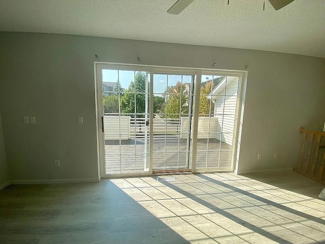 doorway featuring a textured ceiling, ceiling fan, and plenty of natural light