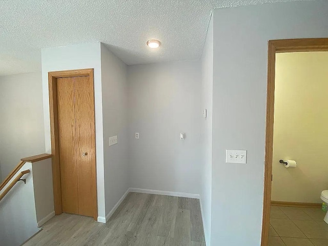 corridor with light hardwood / wood-style floors and a textured ceiling