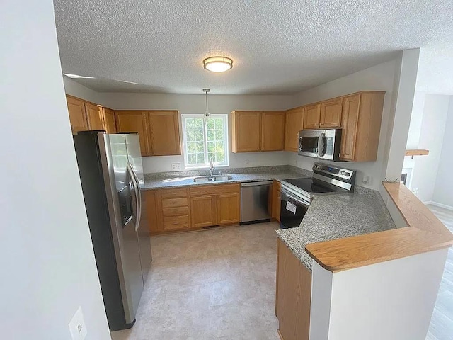 kitchen with appliances with stainless steel finishes, a textured ceiling, pendant lighting, sink, and kitchen peninsula