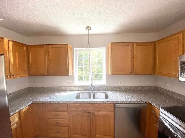 kitchen with a textured ceiling, sink, pendant lighting, and appliances with stainless steel finishes