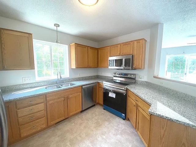 kitchen featuring plenty of natural light, pendant lighting, sink, and stainless steel appliances