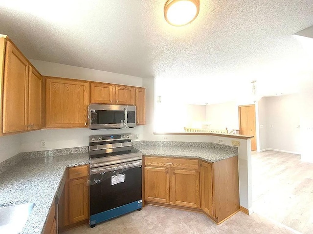 kitchen with kitchen peninsula, a textured ceiling, and appliances with stainless steel finishes