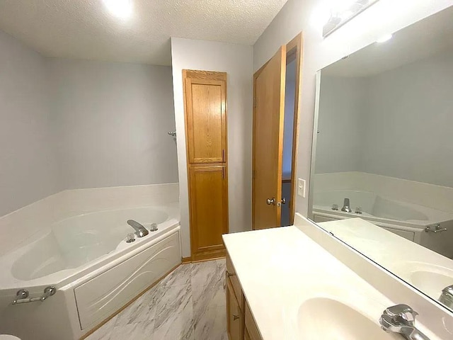 bathroom with vanity, a textured ceiling, and a bath