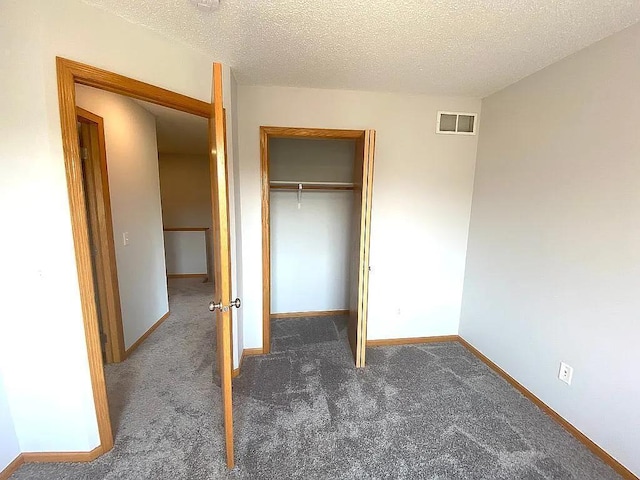 unfurnished bedroom featuring a textured ceiling, a closet, and dark carpet