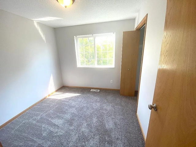 carpeted spare room with a textured ceiling