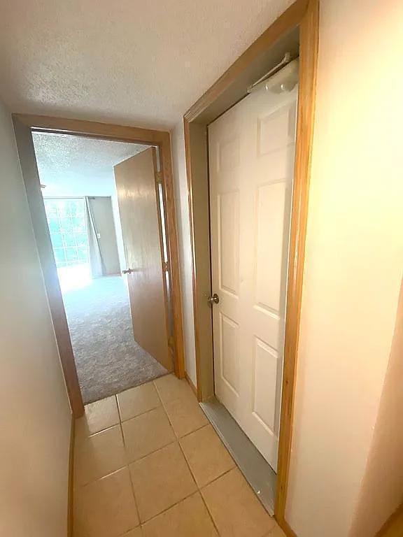 hall featuring a textured ceiling and light tile patterned floors