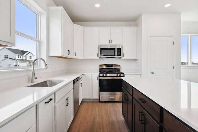 kitchen featuring dark brown cabinetry, sink, hardwood / wood-style floors, white cabinets, and appliances with stainless steel finishes