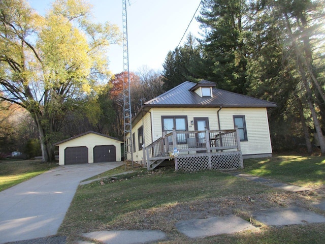 view of front of home with a garage, a front lawn, and an outbuilding