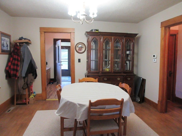 dining room with wood-type flooring and an inviting chandelier