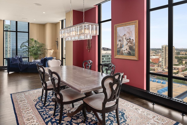 dining area featuring a towering ceiling, dark hardwood / wood-style floors, a chandelier, and a wall of windows