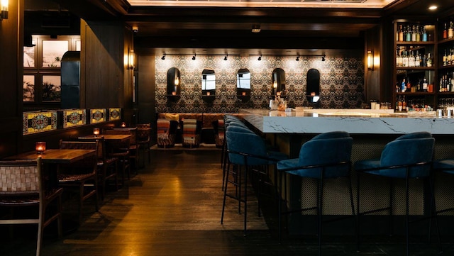 bar with beamed ceiling and dark hardwood / wood-style floors