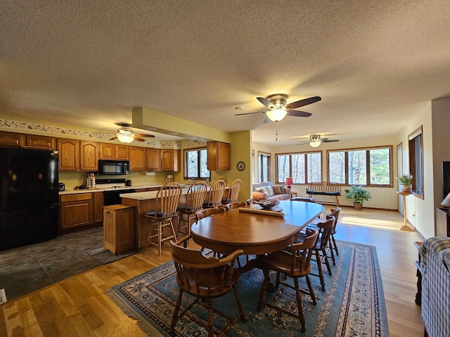 dining area featuring ceiling fan, dark wood-type flooring, and a textured ceiling