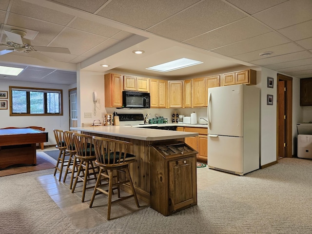 kitchen with kitchen peninsula, a kitchen breakfast bar, a paneled ceiling, light colored carpet, and black appliances