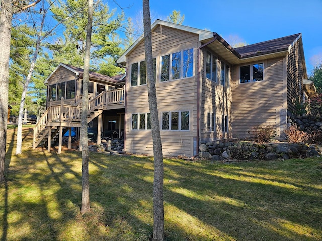 rear view of property featuring a sunroom, stairway, a yard, and a wooden deck