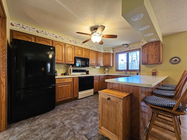 kitchen with black appliances, a textured ceiling, a peninsula, light countertops, and brown cabinets