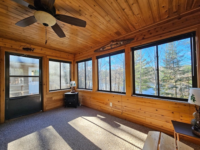 unfurnished sunroom featuring wood walls, carpet, and wooden ceiling