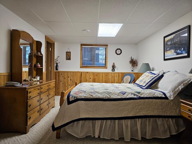 carpeted bedroom featuring a drop ceiling, a wainscoted wall, and wood walls