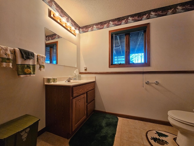 bathroom featuring vanity, toilet, tile patterned floors, baseboards, and a textured ceiling