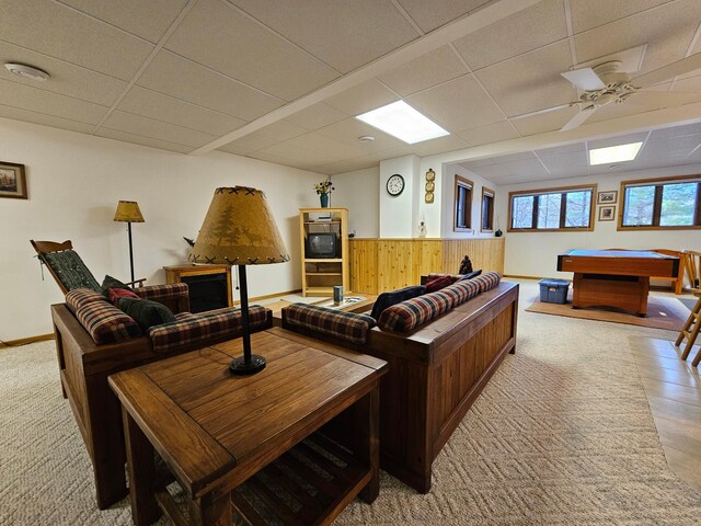 carpeted living area with a paneled ceiling, ceiling fan, wooden walls, billiards, and a wainscoted wall
