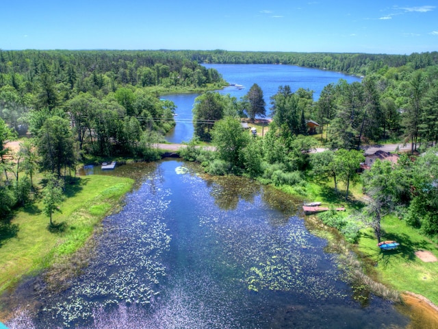 aerial view of property's location featuring a heavily wooded area and a nearby body of water