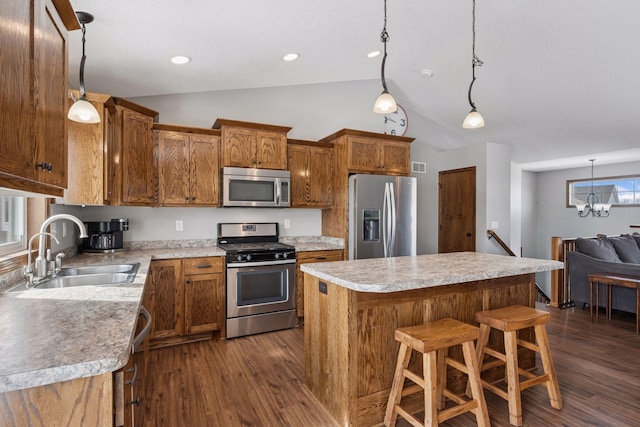 kitchen featuring lofted ceiling, a sink, light countertops, appliances with stainless steel finishes, and a center island