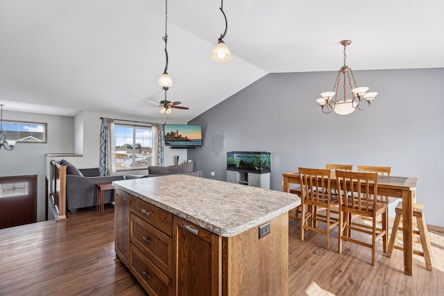 kitchen with a kitchen island, wood finished floors, vaulted ceiling, light countertops, and decorative light fixtures