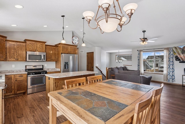 kitchen with appliances with stainless steel finishes, dark wood-style flooring, brown cabinetry, and vaulted ceiling