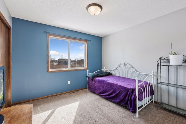 bedroom with carpet, baseboards, and a textured ceiling