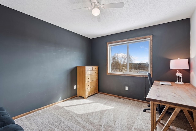 unfurnished office with carpet floors, ceiling fan, baseboards, and a textured ceiling