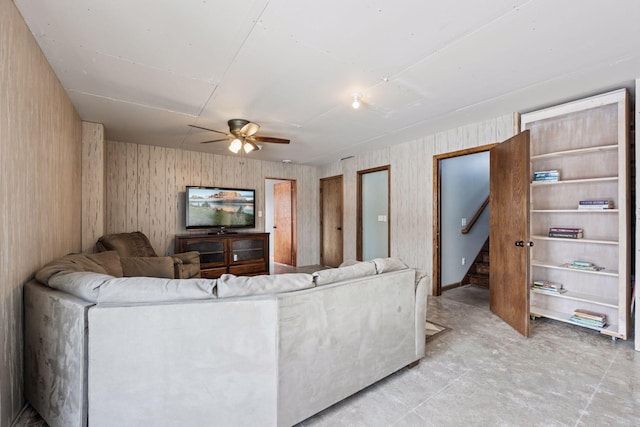 living area featuring a ceiling fan and stairs