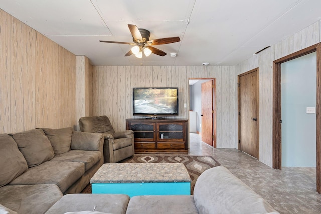 living room featuring a ceiling fan and wood walls