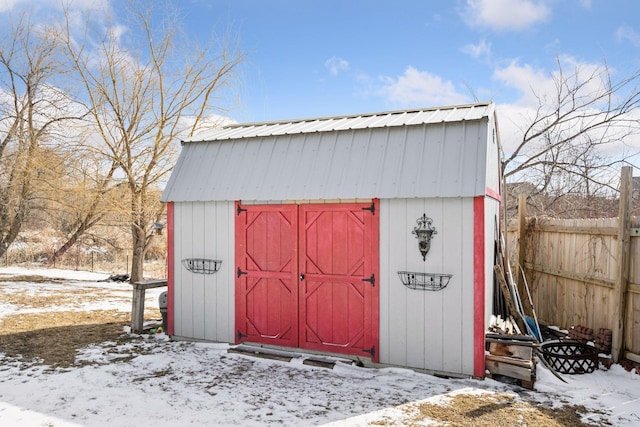 snow covered structure with a storage unit, an outdoor structure, and fence