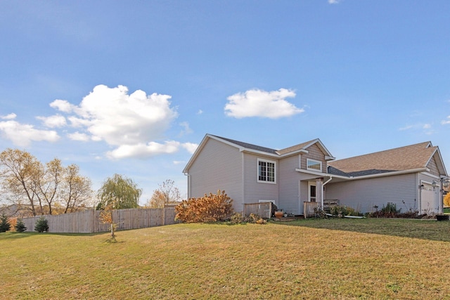 view of home's exterior with an attached garage, fence, and a yard