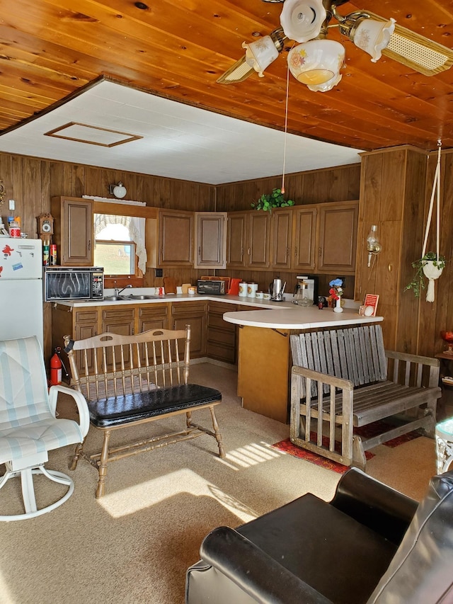 kitchen with wood ceiling, wooden walls, kitchen peninsula, light carpet, and decorative light fixtures