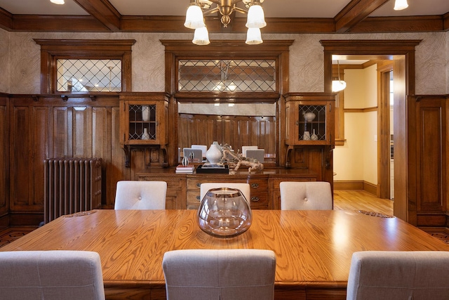 dining space featuring beam ceiling, an inviting chandelier, radiator, and coffered ceiling