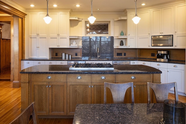 kitchen with stainless steel appliances, white cabinetry, hanging light fixtures, and dark stone counters