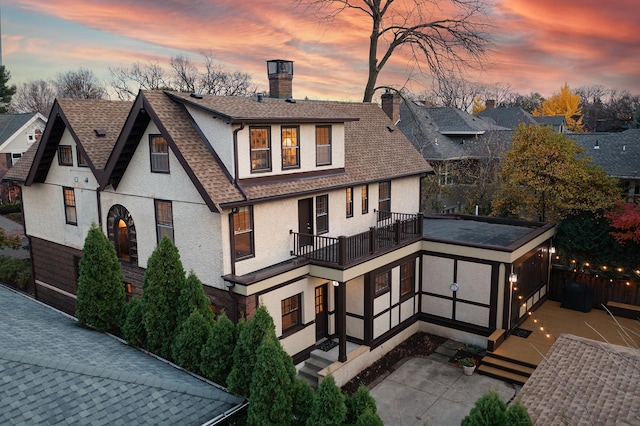 back house at dusk featuring a balcony