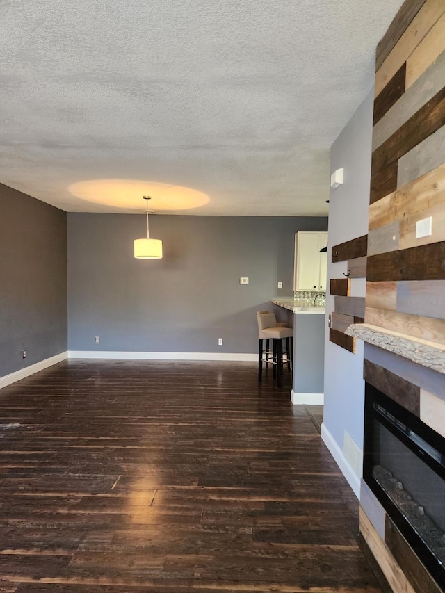 unfurnished living room with dark hardwood / wood-style flooring, a textured ceiling, and a tiled fireplace