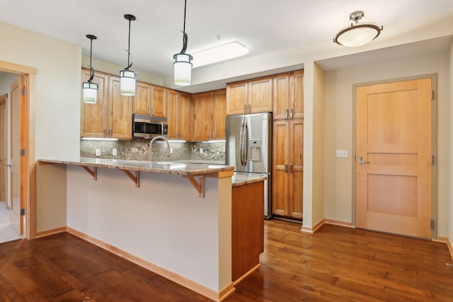 kitchen with stainless steel appliances, dark hardwood / wood-style flooring, kitchen peninsula, hanging light fixtures, and tasteful backsplash