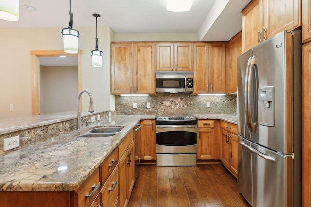 kitchen with dark hardwood / wood-style flooring, sink, light stone countertops, pendant lighting, and appliances with stainless steel finishes