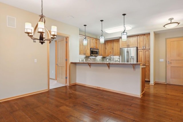 kitchen with kitchen peninsula, stainless steel appliances, and dark hardwood / wood-style flooring