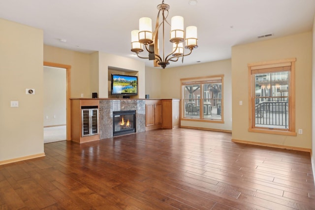 unfurnished living room featuring dark wood-type flooring, an inviting chandelier, and a premium fireplace