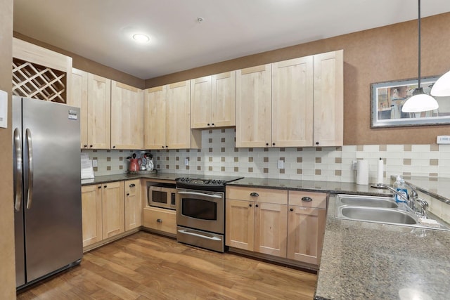 kitchen featuring stainless steel appliances, light wood-type flooring, pendant lighting, sink, and decorative backsplash