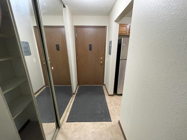 doorway to outside with a textured ceiling and light tile patterned floors