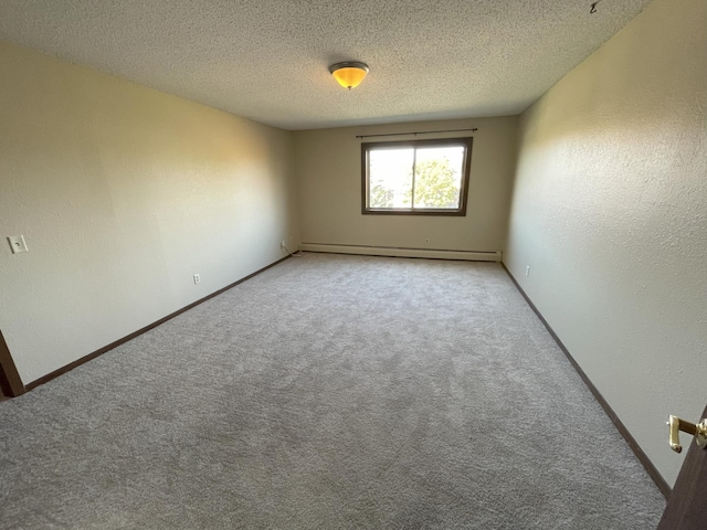 unfurnished room with a baseboard heating unit, carpet floors, and a textured ceiling