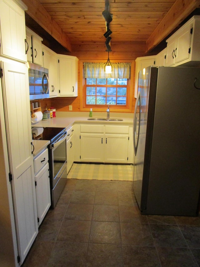 kitchen featuring sink, rail lighting, stainless steel appliances, pendant lighting, and white cabinets